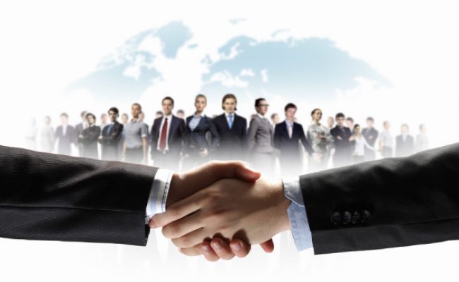 business handshake against white background and standing businesspeople